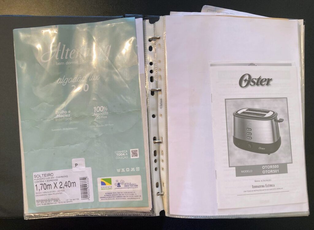 Fichário com sacos plásticos organizando manuais e notas de compra de itens da casa.