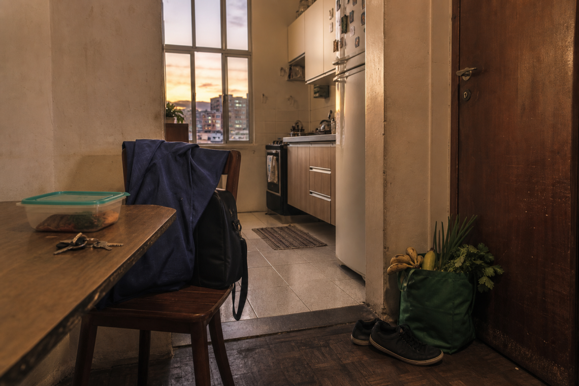 Cena editorial de rotina apertada em casa, com bolsa de trabalho, marmita e compras, para post sobre organização na escala 6x1.