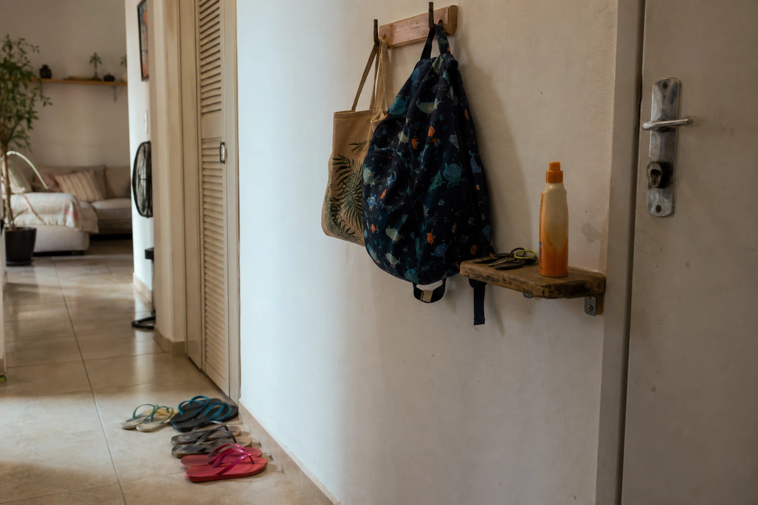 Entrada de apartamento com banco, ganchos e sapatos de uso diário em uma zona curta de chegada.