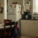 Cozinha de casa com mochila infantil, lancheira e sinais de rotina familiar no fim da tarde.