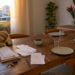 Mesa de jantar de casa real acumulando papéis, bolsa e itens do dia a dia em um lado e mais organizada no outro.